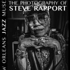 Black-and-white exhibition poster featuring a close-up portrait of a woman wearing artsy square glasses, layered bracelets, rings, and a patterned outfit, resting her chin on her hands. Large text reads “Less Is More: The Photography of Steve Rapport.” Vertical text along the side reads “New Orleans Jazz Museum.” The poster also includes details for an opening reception on April 21, 2026, at 6:00 p.m., featuring Joshua Starkman and friends.