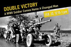 Black-and-white historical photograph of an African American U.S. Army artillery squad operating a large field gun beside a military vehicle on a muddy road in Belgium during World War II, November 1944.