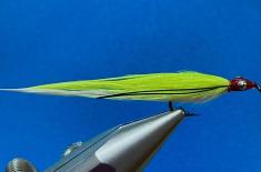Close-up of a bright chartreuse and white fishing fly held in a metal fly-tying vise against a blue background. The fly has a red head, silver eye detail, black accent lines, and a hook extending beneath the body.